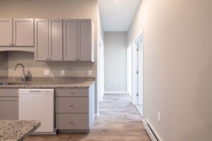 View of hallway and corner of kitchen with gray cabinets at Cottonwood Crossing