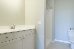 Empty bathroom with white cabinets, shower, toilet
