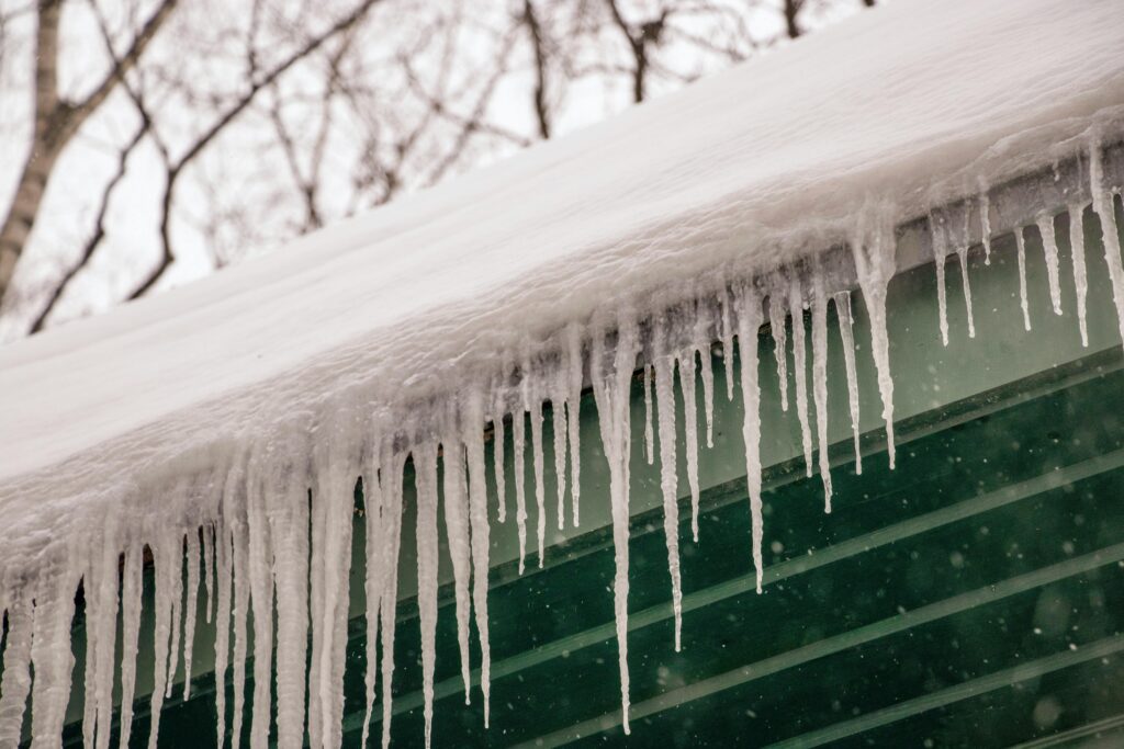 Winter scene of icicles hanging from a rooftop after heavy snowfall.