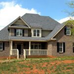 Two-story brick home with shingled roof and front porch — spring property inspection checklist for Vermont landlords