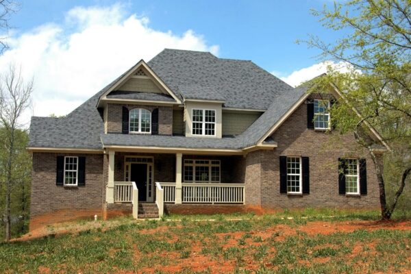 Two-story brick home with shingled roof and front porch — spring property inspection checklist for Vermont landlords
